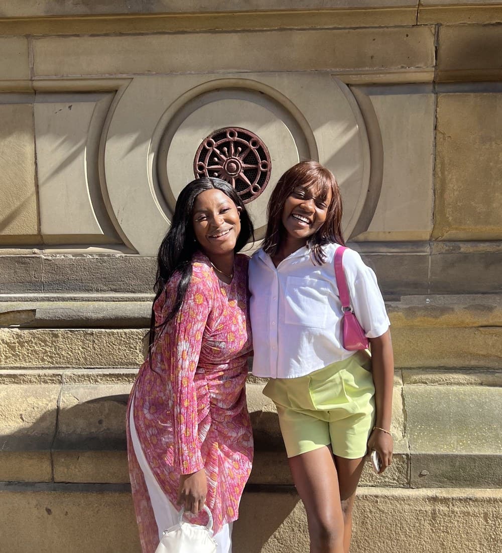 Two members of the community outside a stone building
